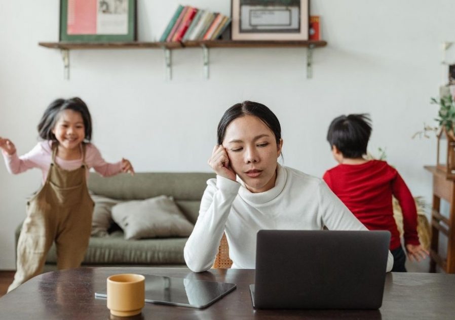 Kids playing whilst woman works on laptop